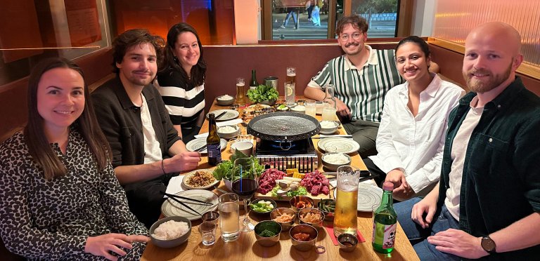 Seks smilende mennekser sitter rundt et bord på en koreansk restaurant.