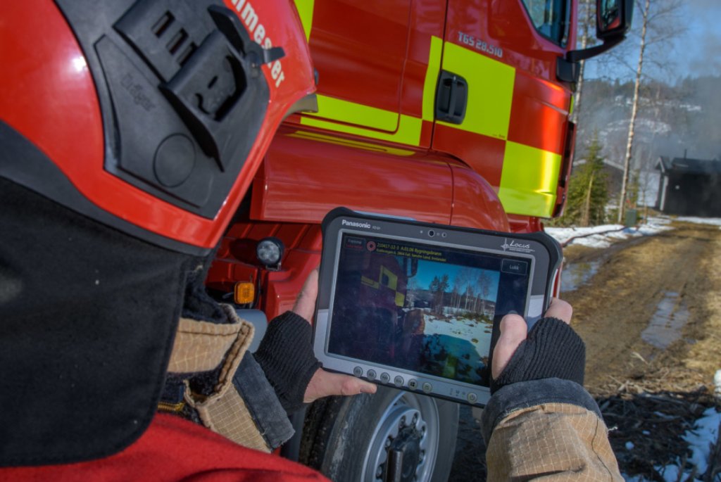 Bilde av brannmann foran en brannbil som holder en Ipad hvor den nye løsningen Bouvet har vært med å utvikle synes. 