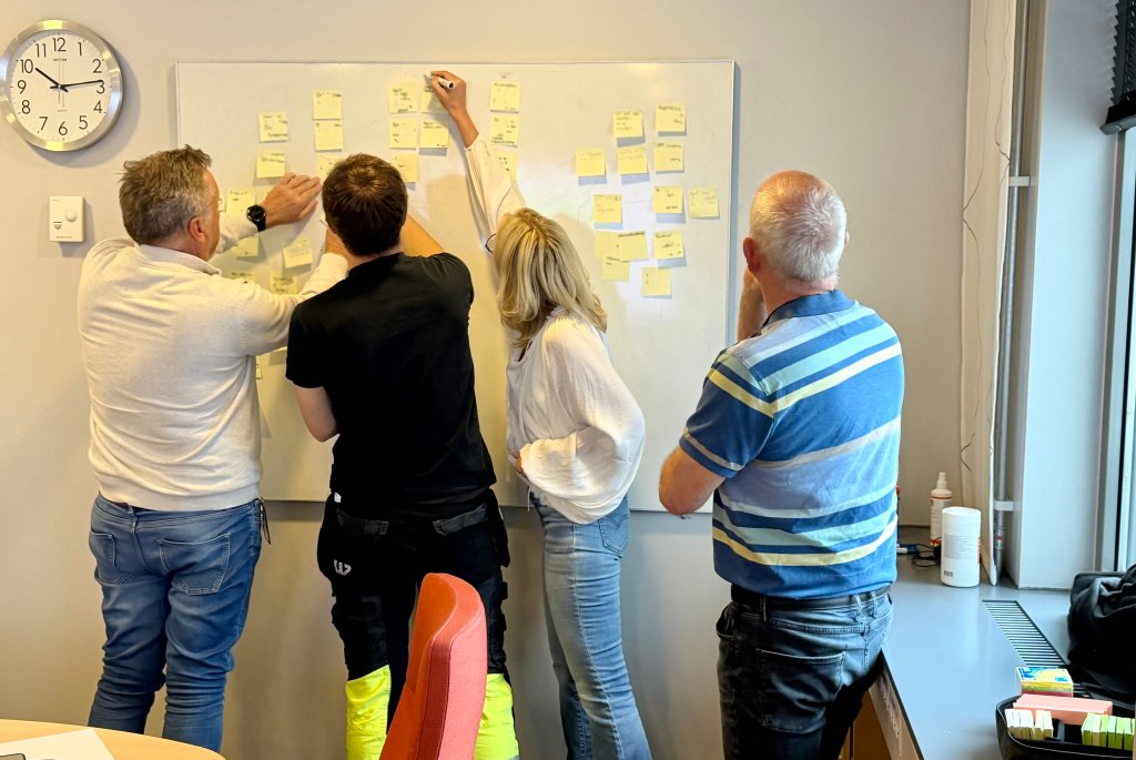 Bilde av fire ansatte hos Returkraft som setter post its på en tavle under AI-workshop med Bouvet 